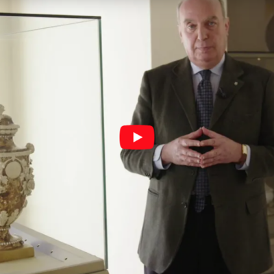 Stefano Papetti che parla accanto a una teca in vetro contenente un'opera in ceramica in stile neoclassico.